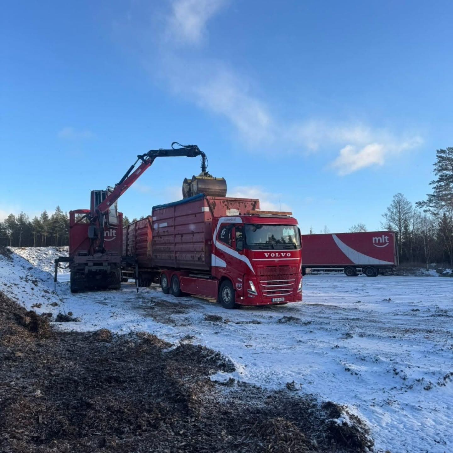 Flisbilen lastar själv med sin kran en vinterdag