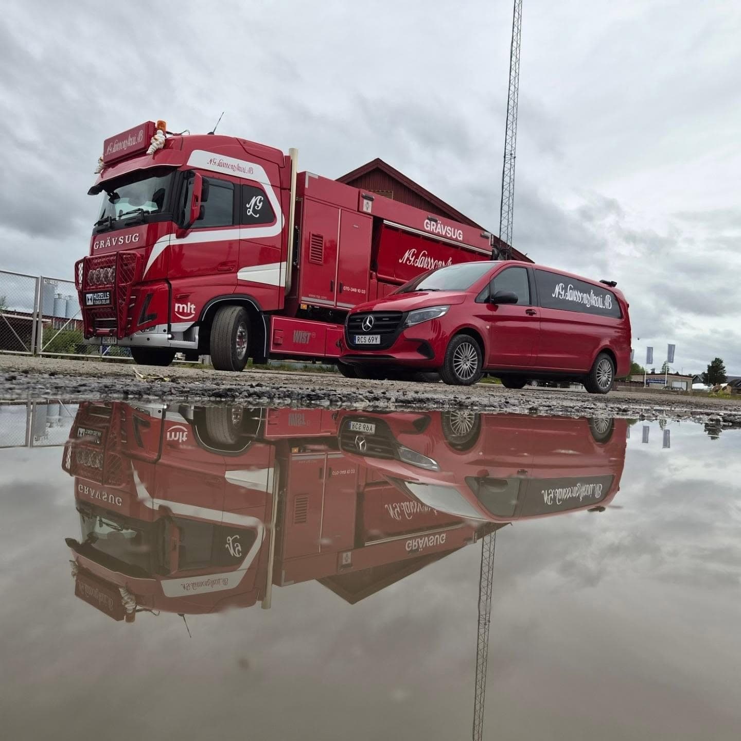 Grävsugen och firmabilen speglas i en vattenpöl