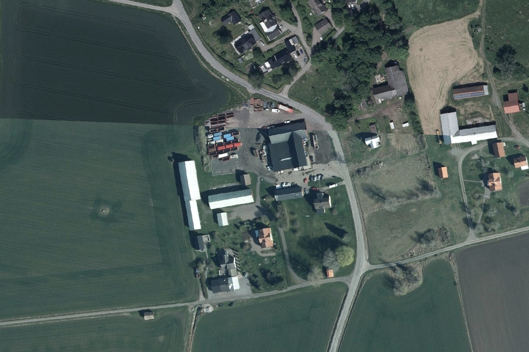 Flygfoto över gården på Gysta 28 i Bälinge med åkeriets bilar och containrar på gårdsplanen